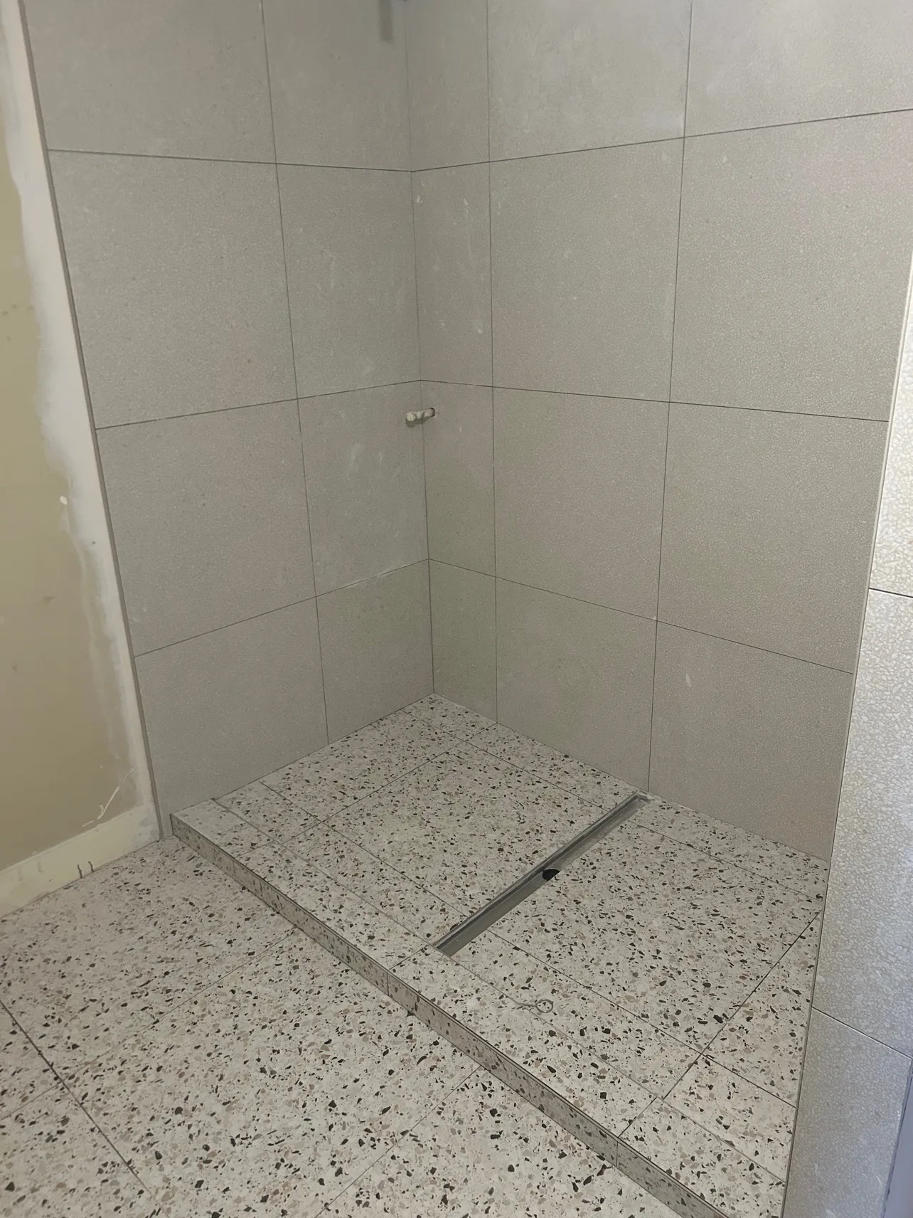 Bathroom during renovation: tiled shower and terrazzo floor