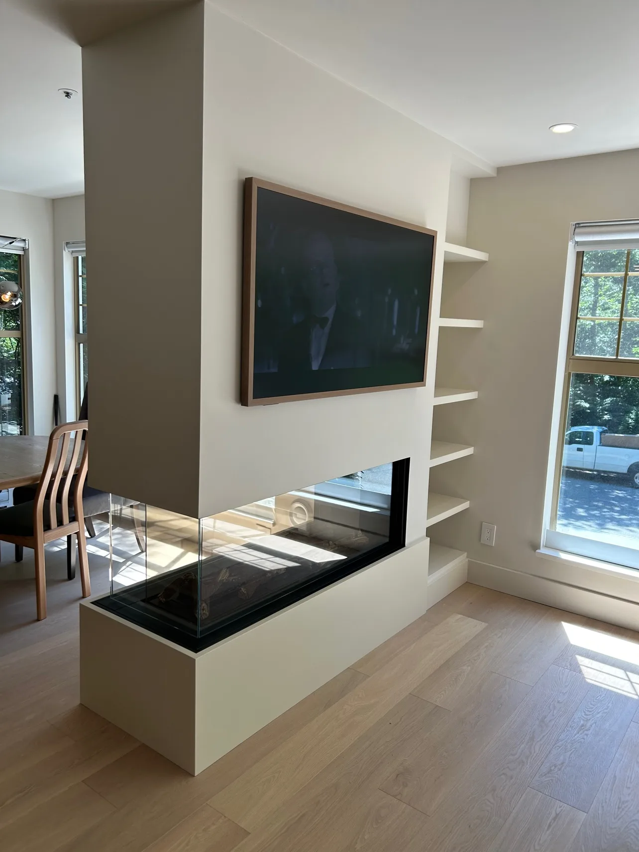 Living room after: three-sided glass fireplace with frame TV above