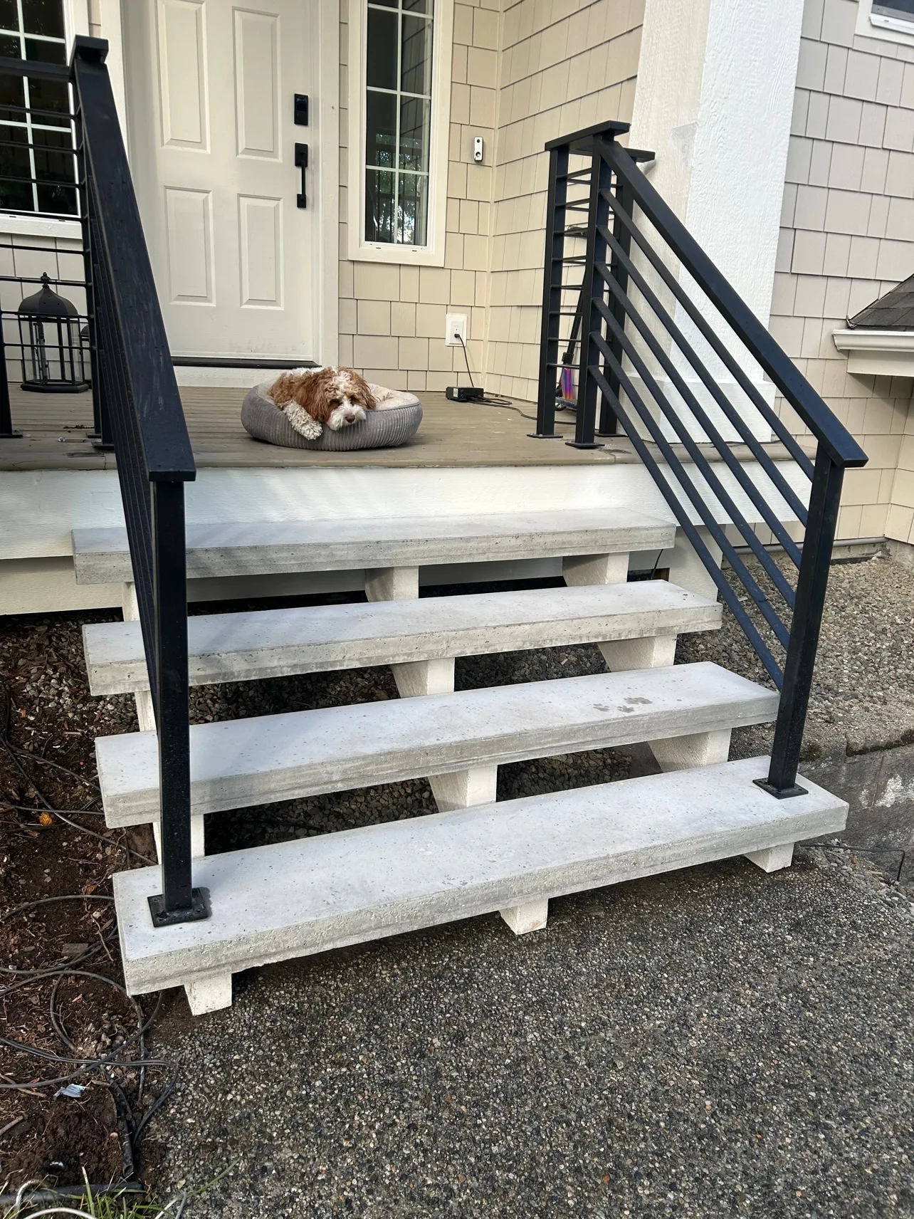Front steps after: smooth concrete steps with black railings